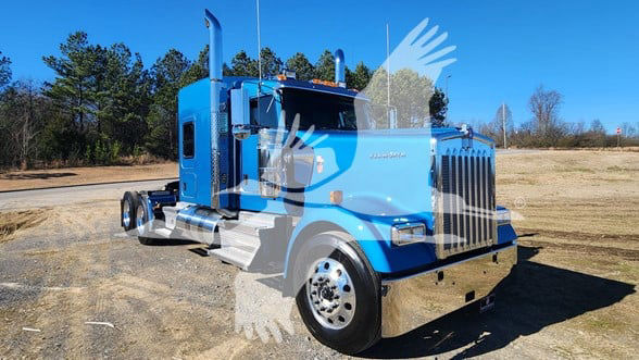 Kenworth W900L truck in blue, side view, with large grille and dual exhaust stacks; visible features include chrome front bumper, fuel tanks, and sleeper cab.