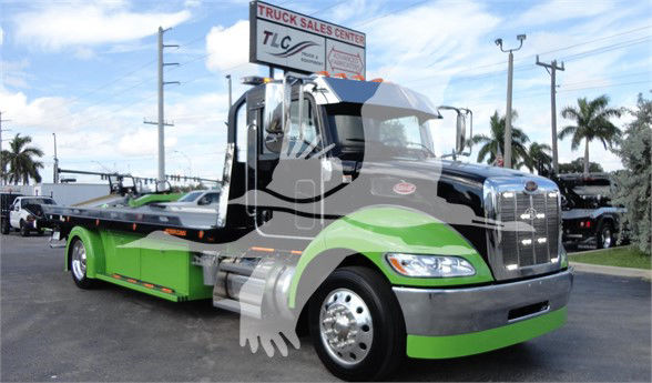 2022 Peterbilt 337 tow truck in green and black with chrome grille, cabinet, and low-profile flatbed.