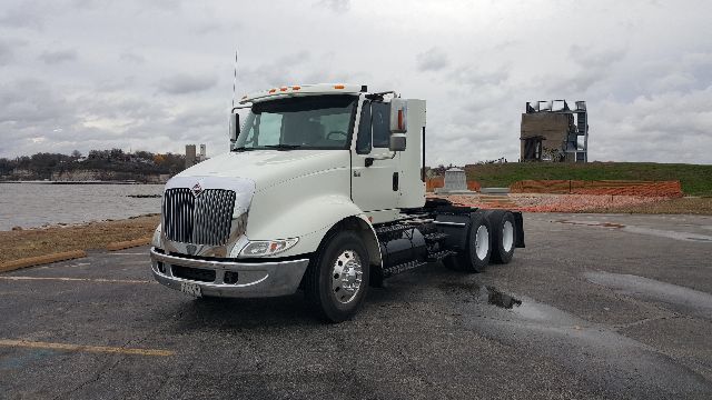 International 8600 conventional daycab truck in a parking lot, white cab, dual rear axles, front grille and headlights visible.