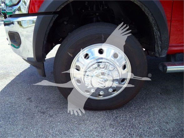 Wheel and front fender of a red Ram 4500 pickup showing a chrome wheel hub and tire. No visible text other than reflections on hub.