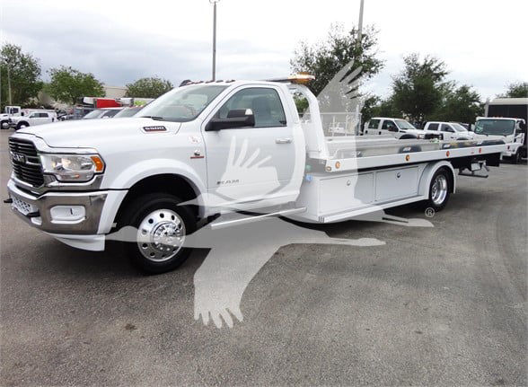 2023 Ram 5500 HD SLT tow truck showing front grille, cab, and flatbed with railing and storage boxes