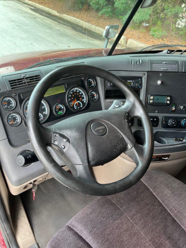 Interior of a 2015 Freightliner Cascadia truck cab showing steering wheel, instrument cluster, and dashboard controls.