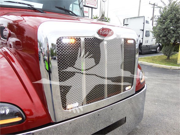 Peterbilt 337 front grille with chrome surround and mesh, headlights on, red truck body, badge on grille.