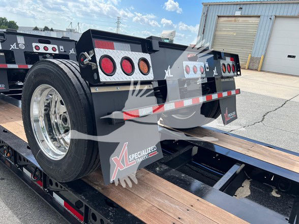 XL Specialized trailer showing spare tire, rear deck with red circular taillights, reflective tape, and XL Specialized Trailers branding.
