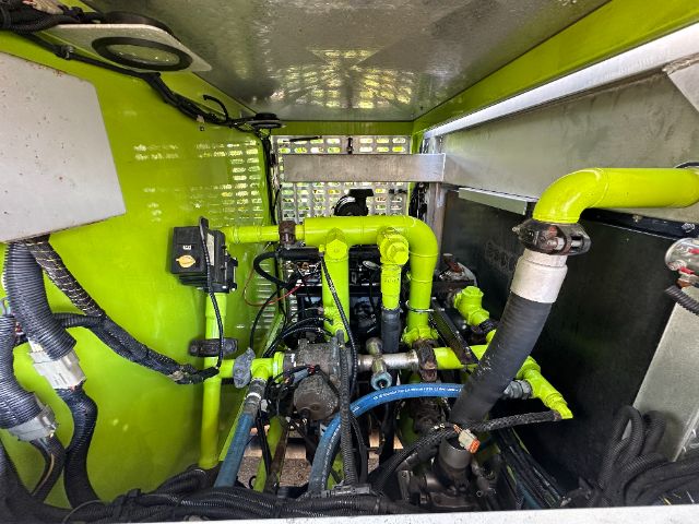 Trucks engine bay of a 2001 Ford F550 with bright green paint. Visible components include hoses, pipes, clamps, and electrical wiring in the engine compartment.
