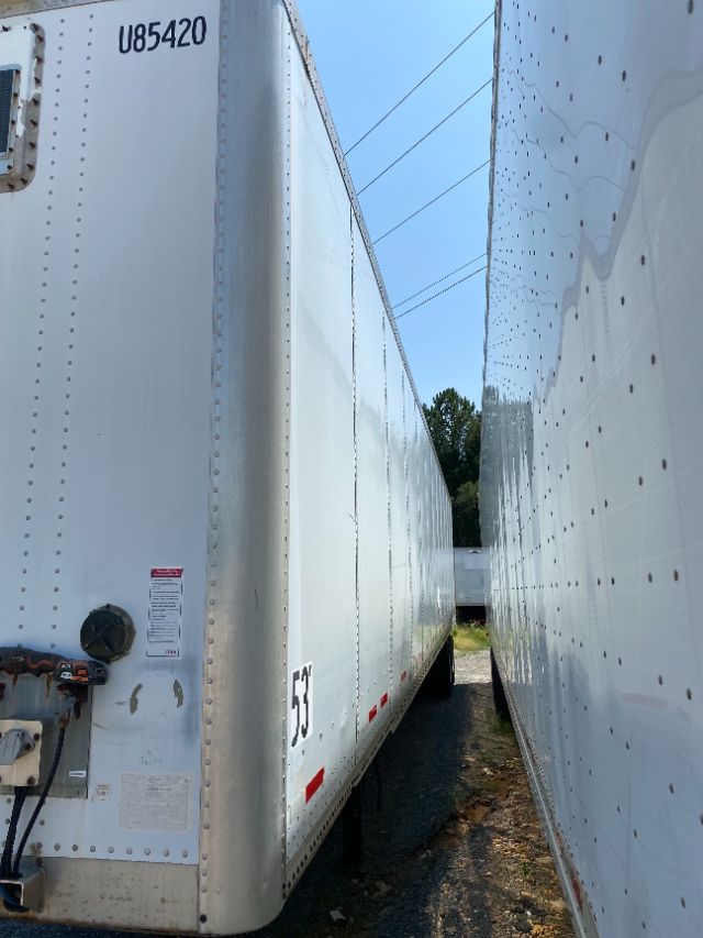 Trailer side view showing white Wabash Duraplate trailer with U85420 code, side step, and red reflective markers.