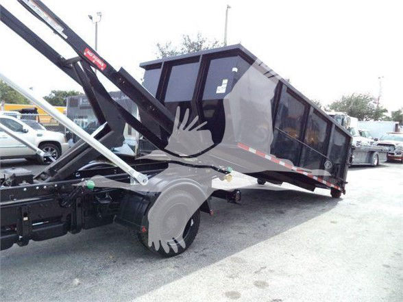 Dump truck trailer with hydraulic lift and dark cargo bed extending to the side, showing large tire and undercarriage components.