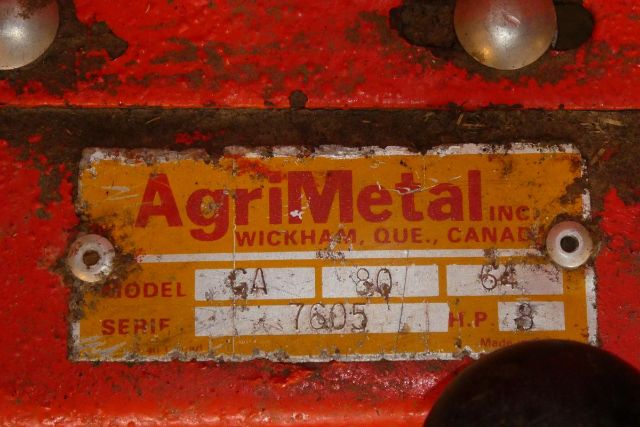 AgriMetal identification plate on red machinery showing model GA and serial 7605 with HP 8, brand AgriMetal Inc. Wickham, Que., Canada.