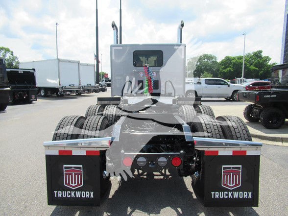 Kenworth W990 cab of a tractor with fifth wheel and dual rear axles, view of rear undercarriage and mudflaps labeled TRUCKWORX.