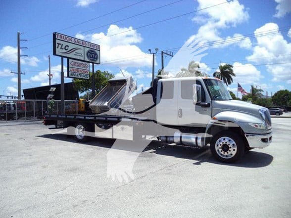 2022 International MV tow truck with flatbed in a lot, side view showing chrome wheels and hydraulic bed.