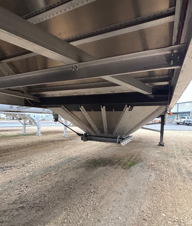 Aluminum hopper trailer underside showing structural frame, triangular hopper walls, support beams, and landing gear leg.