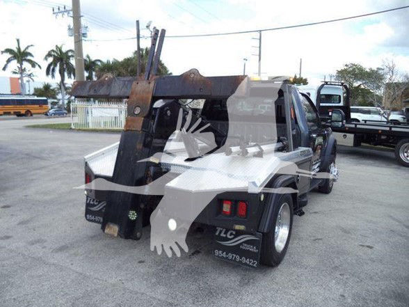 2017 Ford F450 tow truck rear view with rack and hydraulic arm visible; decals and phone numbers on rear fender; taillights and wheel details visible.
