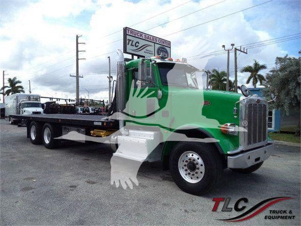 Flatbed tow truck 2014 Peterbilt 367 green cab with white steps and flatbed, showing TLC Truck & Equipment branding in lot
