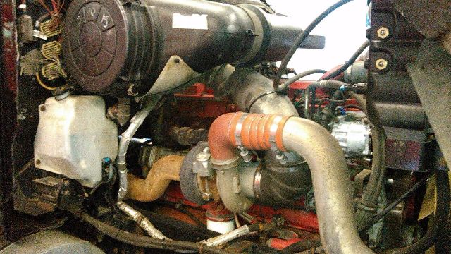 Engine bay of a 2007 International 9900i showing turbocharger piping and hoses.