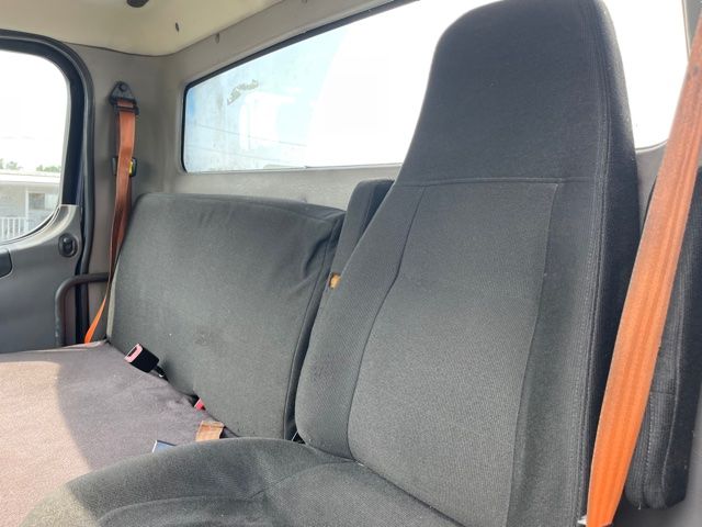 Cab interior of a 2013 Freightliner M2 truck showing front and rear seats with seat belts and window view.