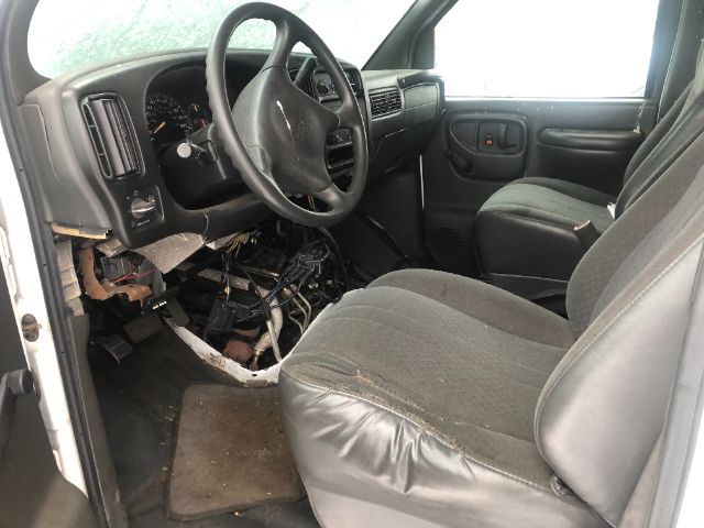 Dashboard and driver’s seat of a 2002 GMC small truck with exposed wiring and missing lower dash panel.
