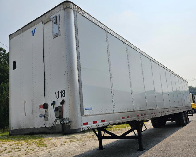 Trailer side view showing Vanguard logo, white riveted trailer with landing legs, VIN and stock number near rear corner.