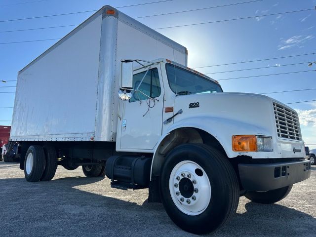 Box truck with white cab and large white box, front grille, side mirrors, and dual rear wheels. Visible text includes '4900' badge on fender and no other legible markings.