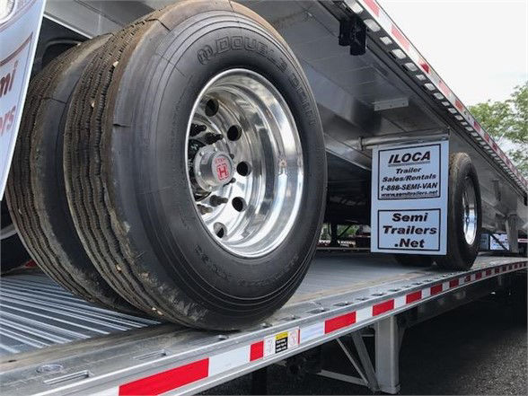 Flatbed trailer with all-aluminum Fontaine 48ft undercarriage showing dual rear tires and reflective safety striping; signs read ILoca Trailer Sales Rentals Semi Trailer s Net.