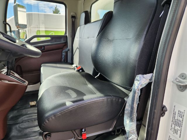 Truck cabin interior showing front seats, steering wheel, and door panel. Visible are seat belts and worn plastic covering near the passenger seat.