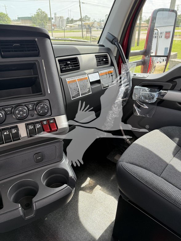 Kenworth T880 interior cab view showing driver-side dash with control knobs, cup holders, and wrapped steering column area.