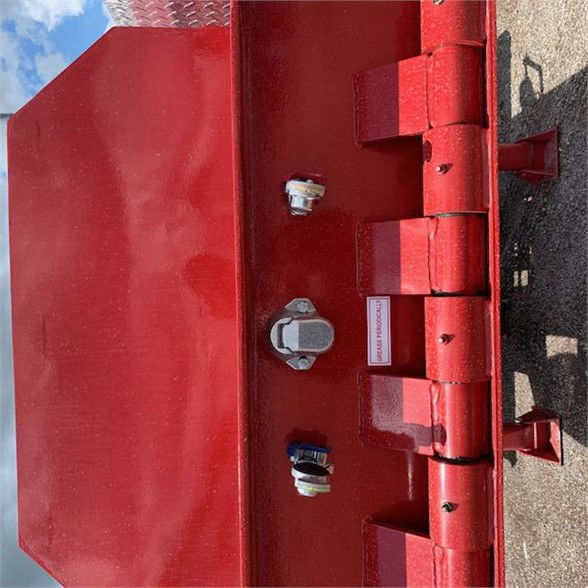 Red drop deck container delivery trailer side showing connection latches and valve ports with reflective stickers.