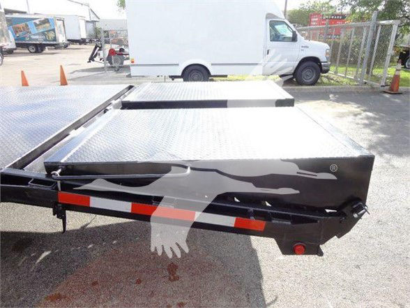 Flatbed truck bed with black flame graphic and reflective strips, metal diamond plate surface, red marker lights, and a white van in background.