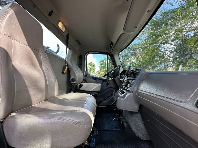 Freightliner 114SD truck cab interior showing driver and passenger seats, dashboard, steering wheel, and center console.