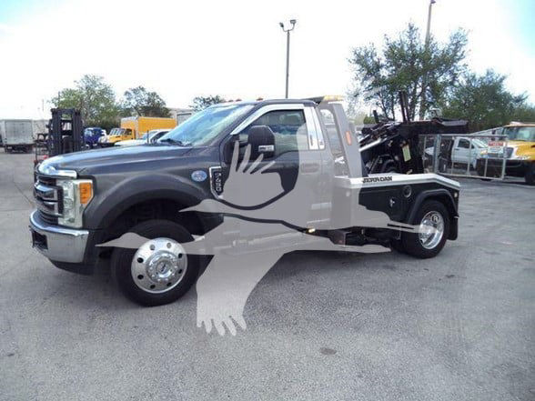 Ford F-450 tow truck with flatbed, metallic gray cab, black accents, and large dual rear wheels. Visible text includes 'Ford' emblem on grille and 'F-450' badge near front door. Towing equipment on bed.