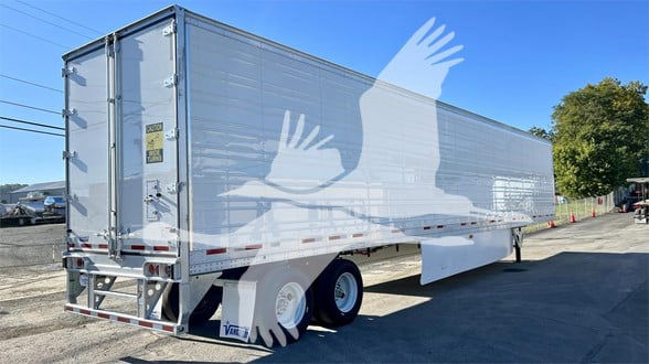 Trailer in a lot showing rear and side with aluminum reefer trailer, Vanguard logo, dual rear doors, and tandem axles.