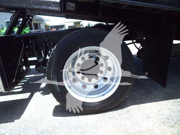 Wheel and tire on a heavy truck trailer with a polished alloy rim and black tire, undercarriage frame visible.