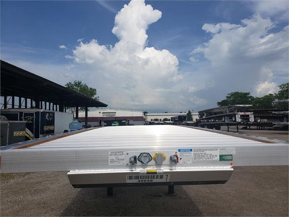Flatbed trailer rear end showing labeling and safety decals on the aluminum facade.