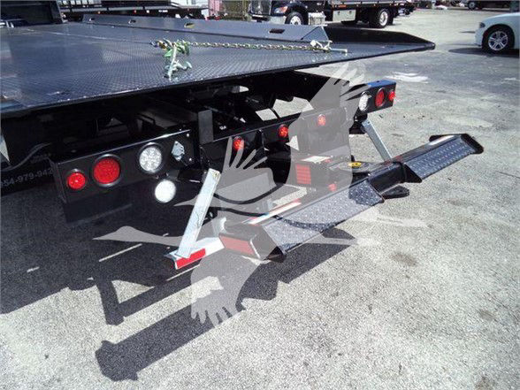 Mack MD6 tow truck rear with hydraulic lift and platform, visible taillights, steps, and rear deck access.