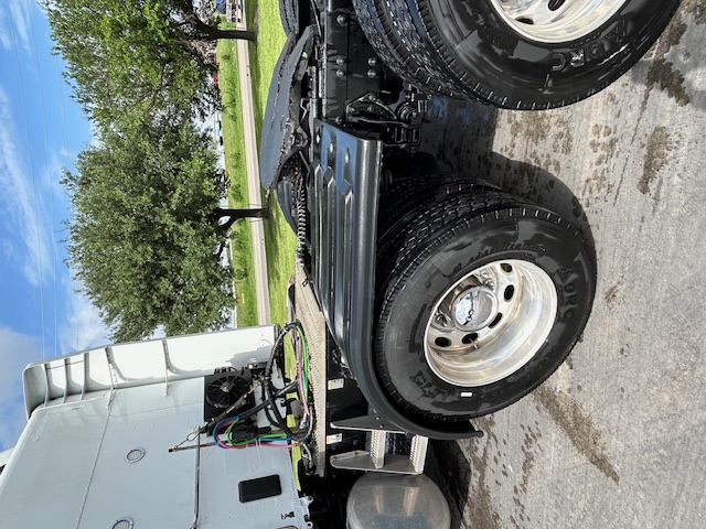 Peterbilt 579 semi-truck tractor rear view showing dual rear wheels, fuel tanks, and part of the cab with wiring harnesses visible.