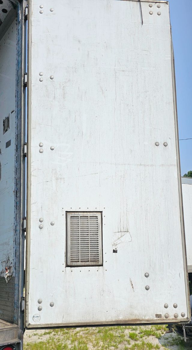 Rear exterior of a white Vanguard VXP trailer door panel showing a small vent near the bottom center and multiple rivets; weathering and dirt marks visible.