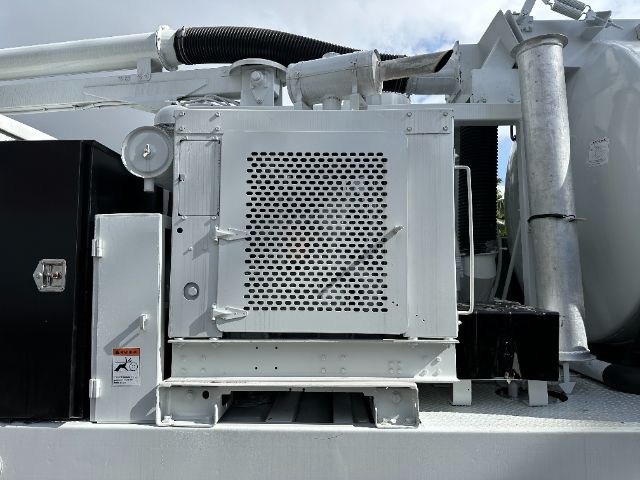 Industrial truck engine bay with a perforated metal radiator guard and surrounding components.