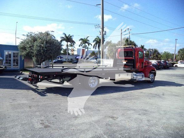 Peterbilt 337 tow truck chassis with lowboy flatbed and red cab, side view.