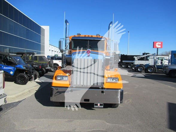 Kenworth W900L conventional sleeper truck front view with orange cab and chrome grille.
