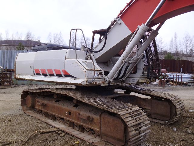 Link-Belt 330LX excavator undercarriage and boom in a yard, with tracked undercarriage and white cab with red stripe.