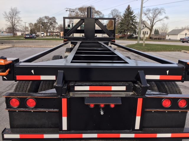 Chassis of a black 2003 Wabash tipper trailer viewed from rear, showing frame rails, rear lights, and reflective safety stripes.