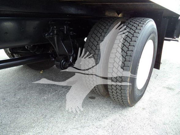Truck rear wheel and suspension visible under a box truck chassis.