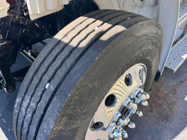 Wheel close-up of a Freightliner M2 106 dump truck showing Bridgestone tire and chrome lug nuts.
