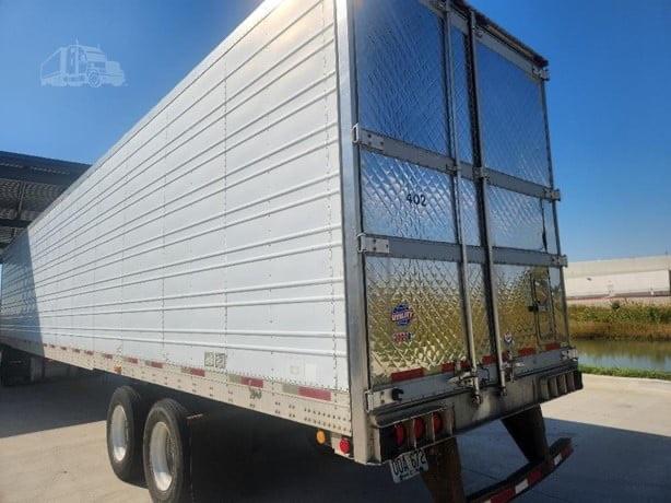 Utility 3000R trailer with aluminum sidewalls and diamond plate rear doors. Dual rear doors, rear lights, and tandem axles visible.
