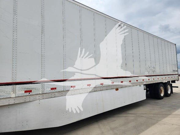 Trailer side view showing Great Dane logo and long silver box trailer with rear wheels and red and white reflective tape.