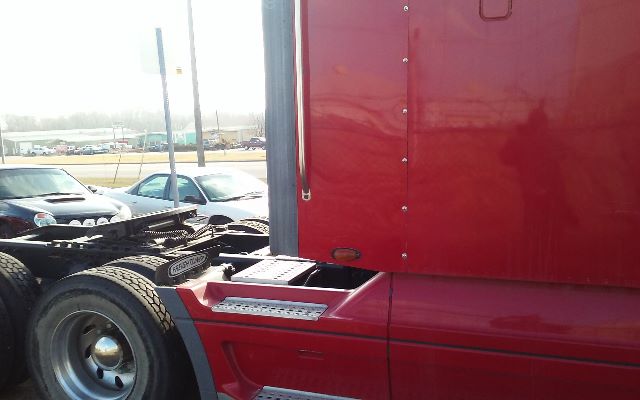 Truck side door and step of a red 2006 Freightliner conventional sleeper with visible rear wheels and chassis.