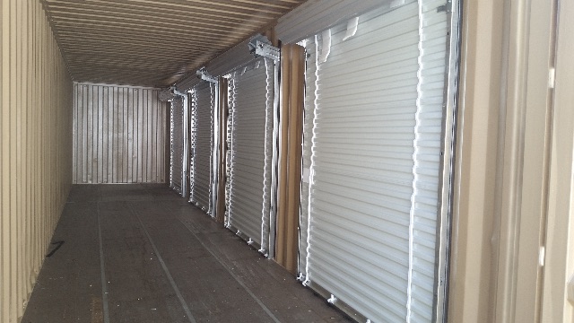 Interiors of a used trailer with multiple silver roll-up doors along side walls.