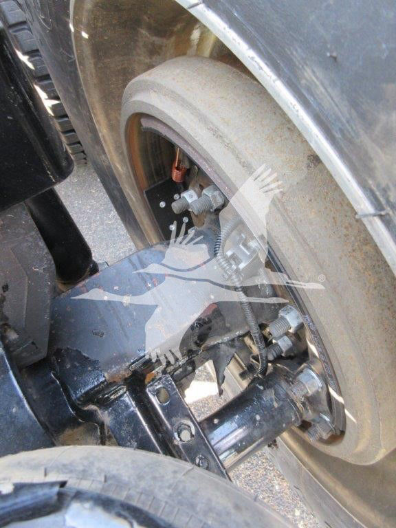 Kenworth W900L front wheel assembly showing brake rotor, caliper, suspension components and steering linkage in view