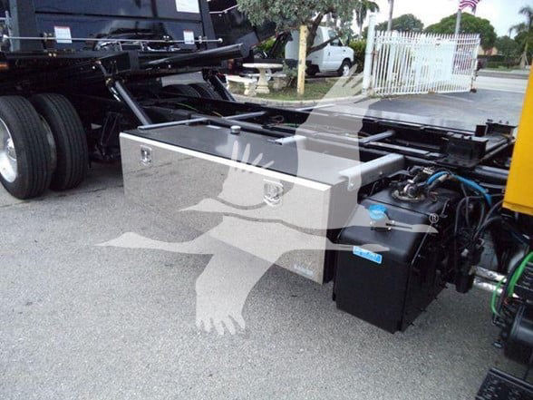 International DURASTAR 4300 truck underside showing auxiliary fuel/air tanks and hydraulic components with blue-capped reservoir.