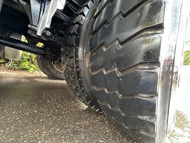 Truck wheel and tire close-up showing large tread with mud and metal rim under a Freightliner M2 chassis.