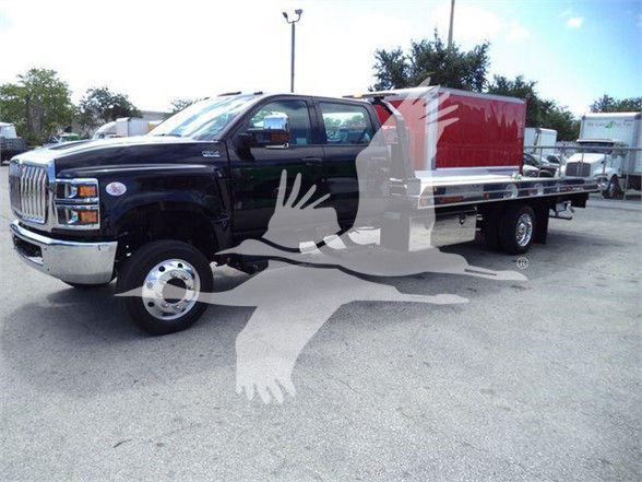 2023 International CV tow truck with black cab and red flatbed with side storage boxes.